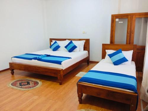 a bedroom with two beds with blue and white pillows at New Lavan Bolgoda in Piliyandala