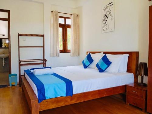 a bedroom with a large bed with blue and white pillows at New Lavan Bolgoda in Piliyandala
