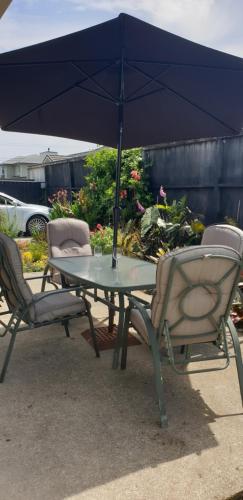 a table with two chairs and an umbrella at Warm & welcome on Whiteley in New Plymouth