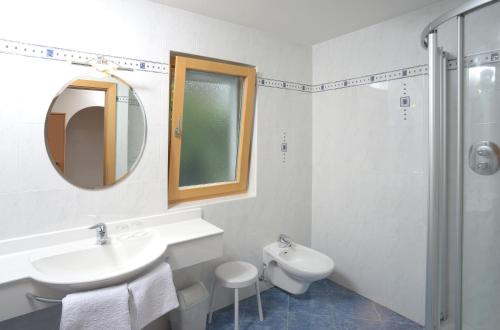 a white bathroom with a sink and a mirror at Kampflhof Apartments in Schenna