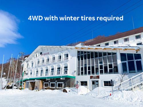 a white building in the snow with the words avid with winter tires required at Shiga Swiss Inn in Yamanouchi