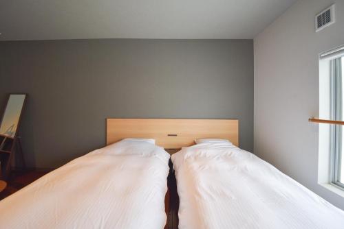 two beds in a bedroom with a wall at Setolive by 4S STAY in Takamatsu