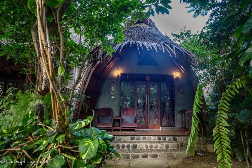 a house with chairs in the middle of a forest at Green Travelodge Bukit Lawang in Bukit Lawang
