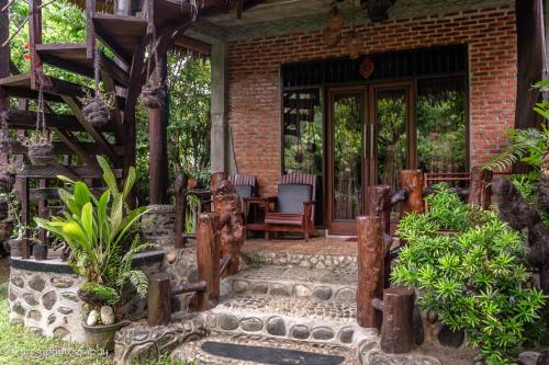 a porch of a house with a chair and a table at Green Travelodge Bukit Lawang in Bukit Lawang