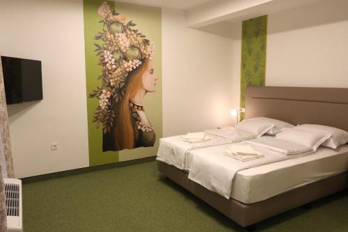 a bedroom with a bed with a painting of a woman at VINOTEL BRZICA Aljmaš in Aljmaš