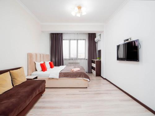 a bedroom with a bed and a couch at Appartments " Zhetysu-4" in Almaty