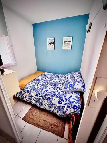 Cette petite chambre comprend un lit et un mur bleu. dans l'établissement Petit Cocon près de la grande plage, à Saint-Hilaire-de-Riez