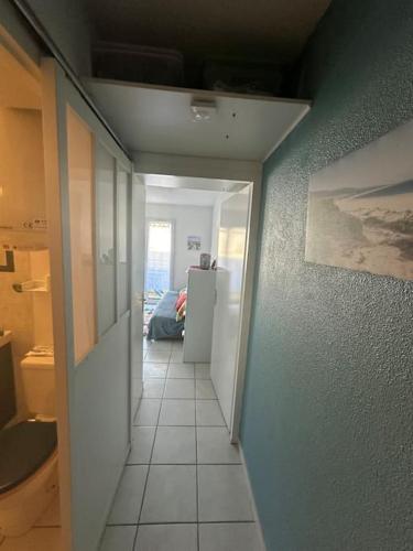 un couloir menant à une cuisine équipée d'un réfrigérateur dans l'établissement Petit Cocon près de la grande plage, à Saint-Hilaire-de-Riez
