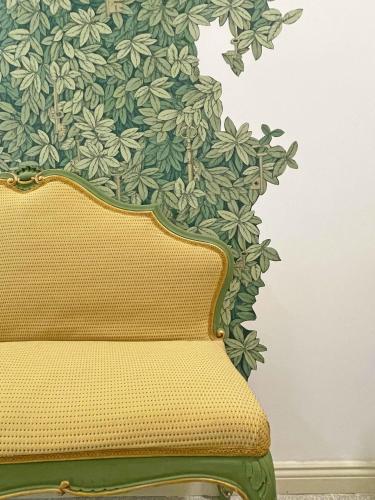 a yellow couch in front of a green wall at ISOLA - Smart ApartHotel in Messina