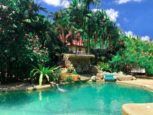 a swimming pool in front of a house with palm trees at Shanti Lodge Phuket in Chalong 