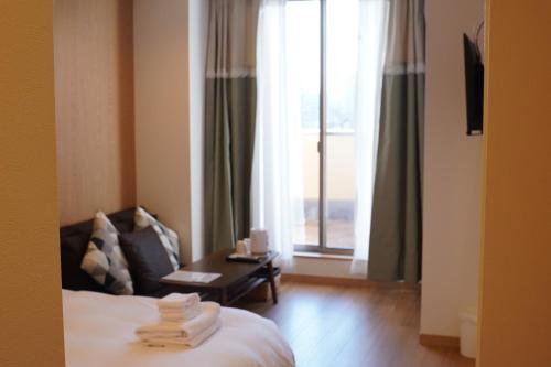 a hotel room with a bed and a table and a window at Softlight Inn Asakusa Tokyo in Tokyo