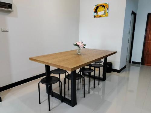a wooden table with chairs and a vase of flowers on it at MikaHouse in Betong
