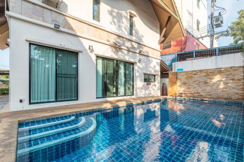 a swimming pool in front of a building with a house at 芭提雅近好莱坞45号三卧别墅 in Pattaya