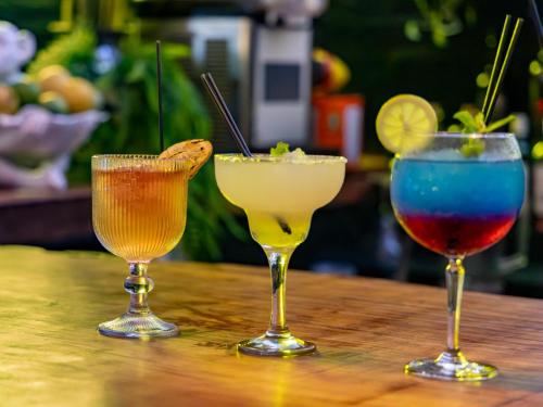 three cocktails sitting on a wooden table at Da Loose Mongoose in White River