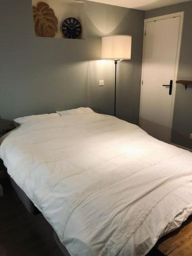 a white bed in a room with a clock on the wall at Appart très cosy en rez de jardin in Le Plessis-Robinson