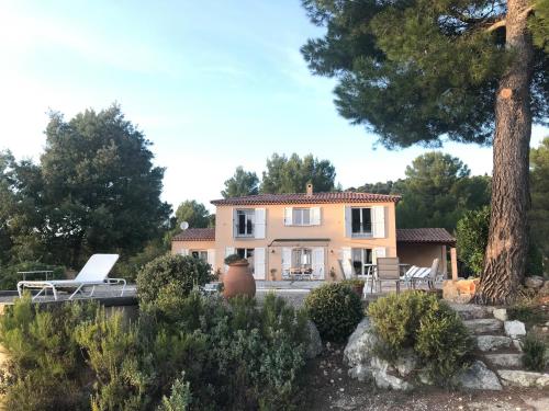 ein großes Haus mit einem Baum davor in der Unterkunft Villa "Le Sortilège" vue panoramique et piscine in Tourtour