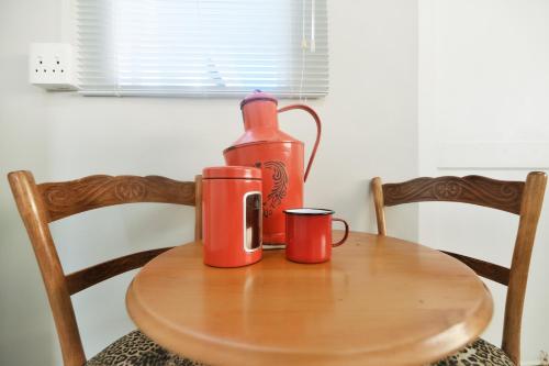 two red cups on a wooden table with a bottle at Hugo Haven in Bredasdorp