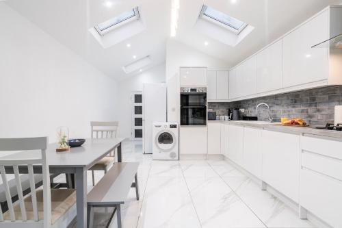a kitchen with white cabinets and a table at Albert Street Retreat, Windsor in Windsor