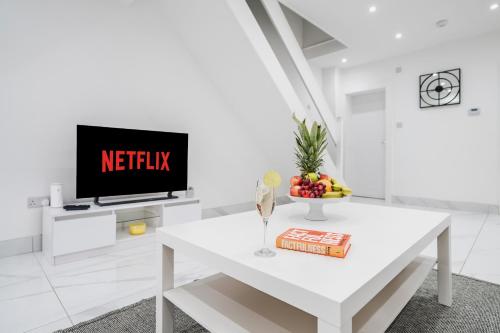 a white living room with a white table and a tv at Albert Street Retreat, Windsor in Windsor