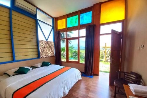 - une chambre avec un lit et des baies vitrées colorées dans l'établissement Hotel Syariah Simply Homy dekat Yogyakarta International Airport, à Glagah