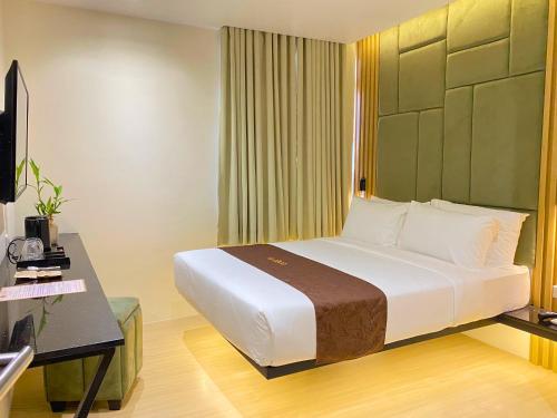 a hotel room with a large bed and a desk at El Coco Boutique Hotel in Ibabang Talim