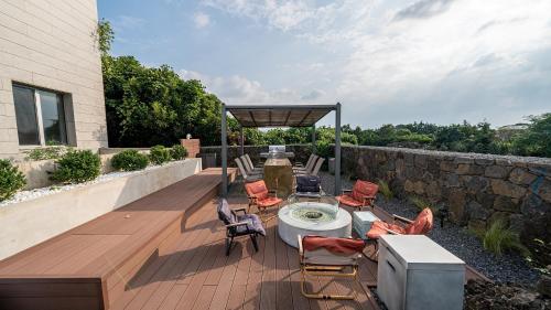 a patio with chairs and a table and a stone wall at Eudaimonia Poolvilla Jeju 에다모니아 함덕풀빌라 in Jeju