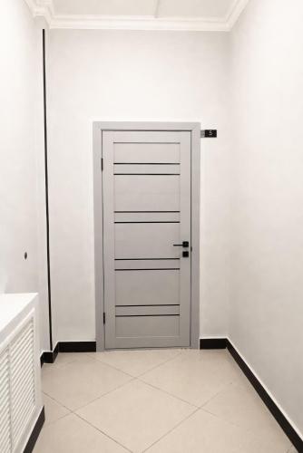 a door in a white room with a tile floor at The Rest Hostel in Astana