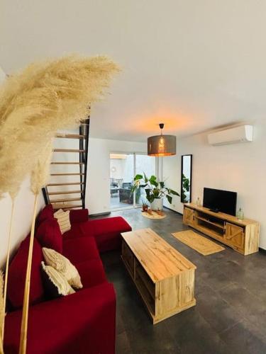 a living room with a red couch and a staircase at Appartement en petite Camargue in Saint-Laurent-dʼAigouze
