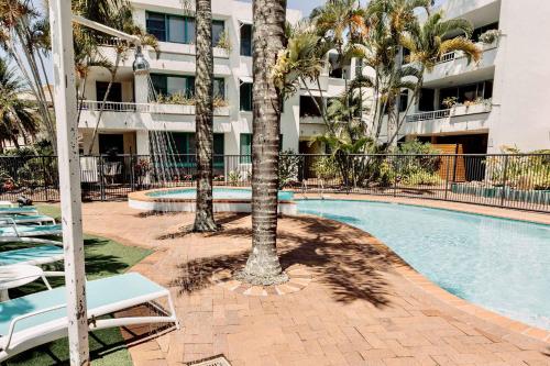 una piscina con palme e un edificio di Headlands Beachside Retreat - 50 metres to beach ad Alexandra Headland