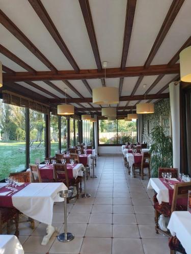 une salle à manger avec tables, chaises et fenêtres dans l'établissement Manoir de la Roche Torin, The Originals Relais, à Courtils