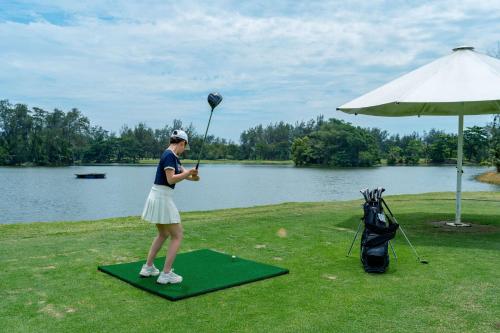 a woman standing on a green mat with a golf ball at Shangri-La Rasa Ria, Kota Kinabalu in Kota Kinabalu