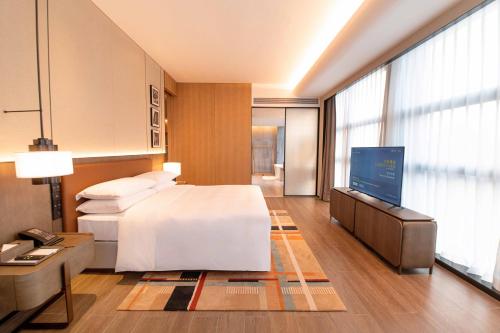 a hotel room with a bed and a flat screen tv at Courtyard by Marriott Nanning Wuxiang in Nanning