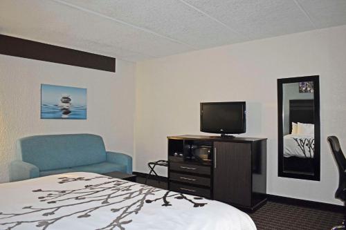 a hotel room with a bed and a tv and a chair at Sleep Inn & Suites West Knoxville in Knoxville