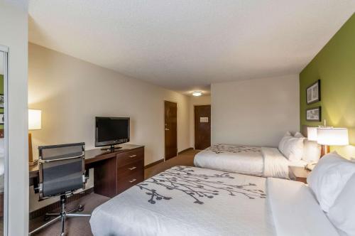 a hotel room with two beds and a flat screen tv at Sleep Inn & Suites Harrisonburg near University in Harrisonburg
