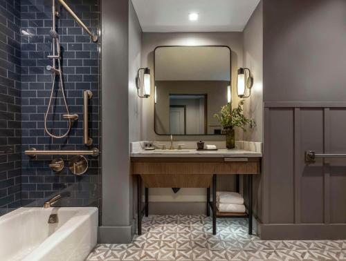 a bathroom with a tub and a sink and a mirror at Thompson Savannah, by Hyatt in Savannah