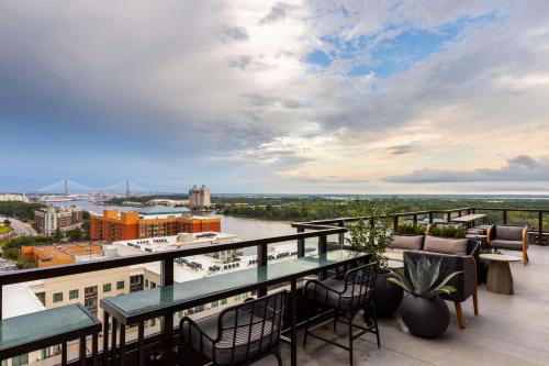 a balcony with tables and chairs and a view of a river at Thompson Savannah, by Hyatt in Savannah