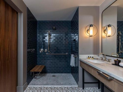 a bathroom with a sink and a shower with blue tiles at Thompson Savannah, by Hyatt in Savannah
