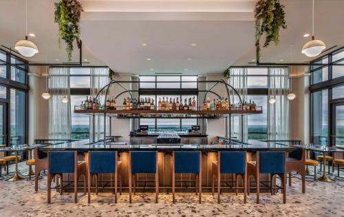 a bar with chairs and tables in a room with windows at Thompson Savannah, by Hyatt in Savannah