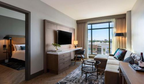 a hotel room with a couch and a bed and a television at Thompson Savannah, by Hyatt in Savannah