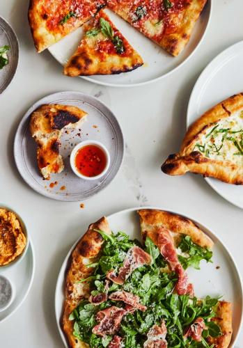 a table topped with plates of pizza and dips at Thompson Savannah, by Hyatt in Savannah