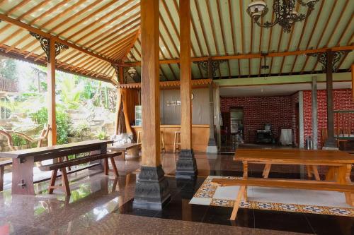 - un grand pavillon avec des bancs en bois et une table dans l'établissement Hotel Syariah Simply Homy dekat Yogyakarta International Airport, à Glagah