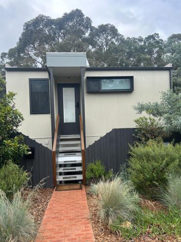 a tiny house with a black fence and a staircase at Bushland setting close to Sydney CBD- stand alone apartment in Sydney