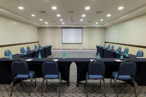 a conference room with a table and chairs and a screen at Radisson Hotel Curitiba in Curitiba