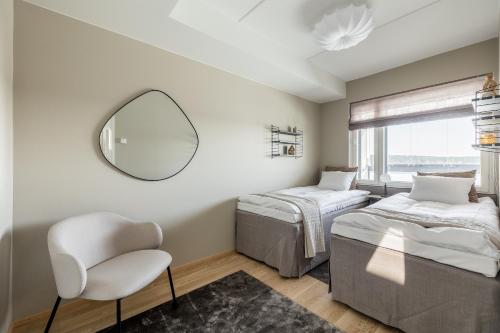 a bedroom with two beds and a mirror and a chair at Penthouse Valsa in Rovaniemi