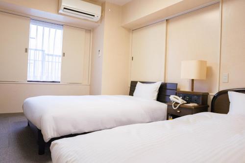 a hotel room with two beds and a phone at Hotel Alpha Inn Akita - Vacation STAY 67286v in Akita