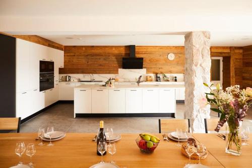 a kitchen with a wooden table with wine glasses at chalet la forgerie Piscine Jacuzzi Cinéma in La Forge