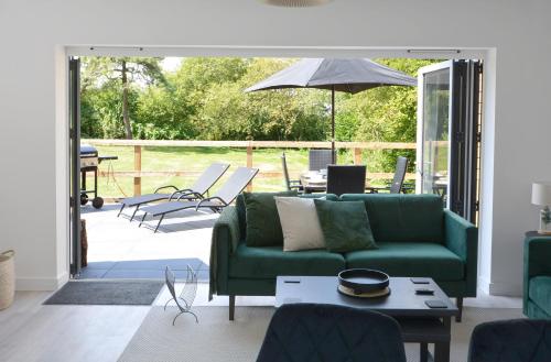 a living room with a green couch and a patio at Tree Tops in Lulsgate Bottom