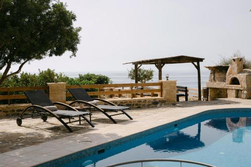 a pair of chairs sitting next to a swimming pool at Greco Levantes Villas in Triopetra