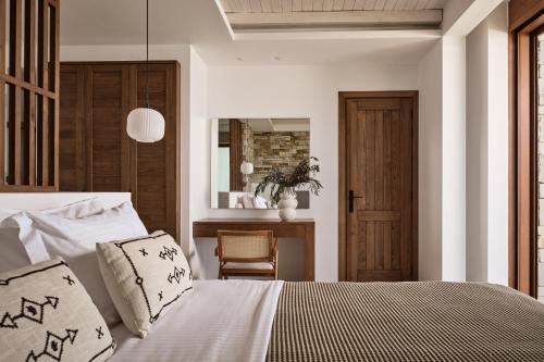 a bedroom with a bed and a chair and a mirror at Thesan Villas in Marathias