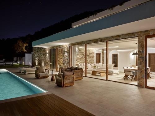 an outdoor patio with a swimming pool at night at Thesan Villas in Marathias